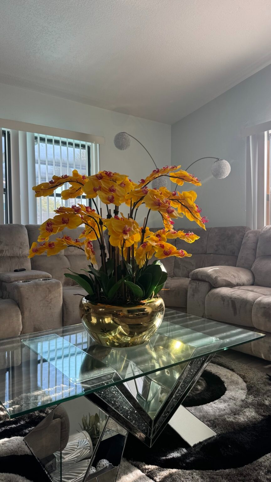 Kaskadierende gelbe Orchideen in einer goldfarbenen Edelstahlvase